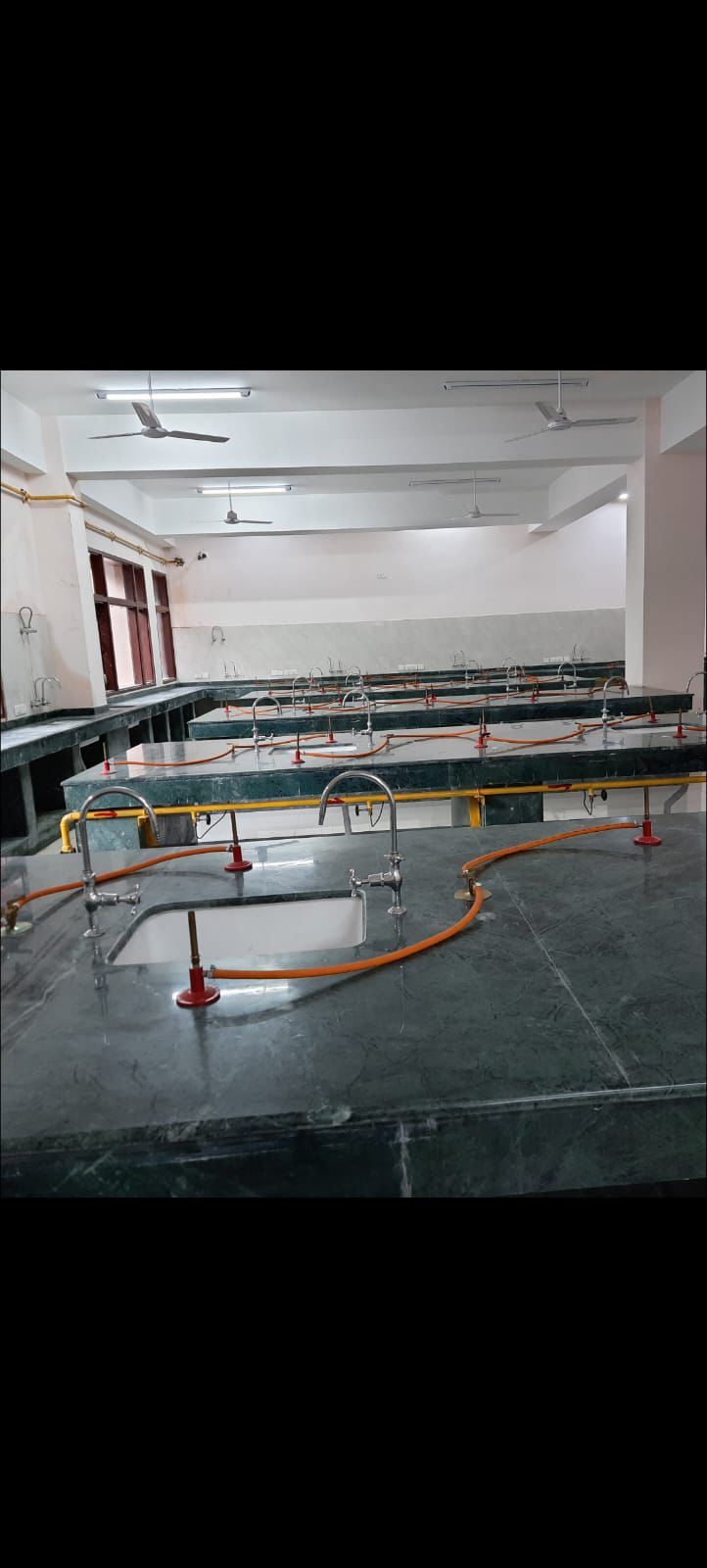 Laboratory room gas pipeline installation with orange hoses across benches